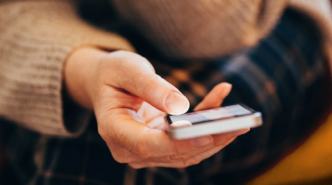 Frauenhand mit Smartphone in der Hand in der Frontalperspektive
