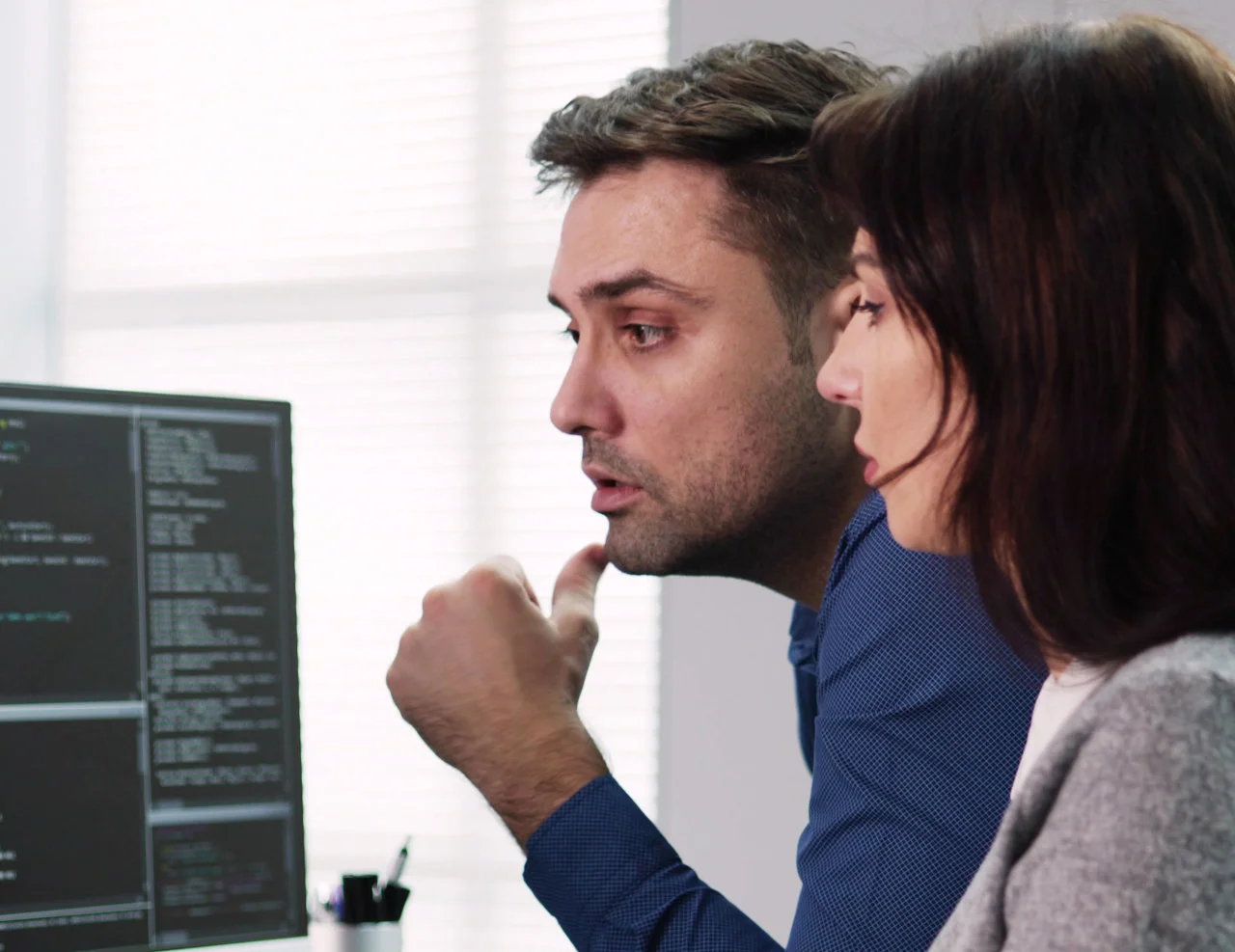 Zwei Entwickler besprechen Quellcode auf einem Computermonitor