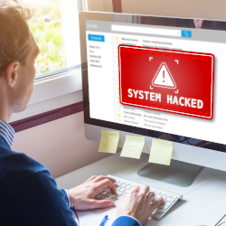 Person betrachtet einen Computerbildschirm mit der Warnung „System gehackt“