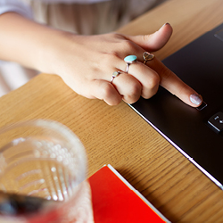 Woman&rsquo;s hand with extended index finger using a fingerprint sensor to unlock a laptop