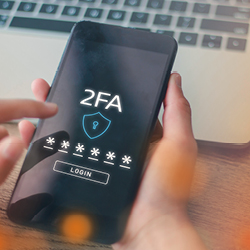 Eine Person h&auml;lt ein Smartphone in der Hand und f&uuml;hrt eine Zwei-Faktor-Authentifizierung durch