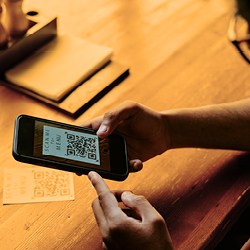 Eine Person scannt in einem Restaurant einen QR-Code auf dem Tisch