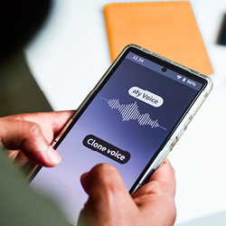 Smartphone in der Hand einer Person zeigt eine App mit der Beschriftung &bdquo;My Voice&ldquo; und &bdquo;Clone voice&ldquo;